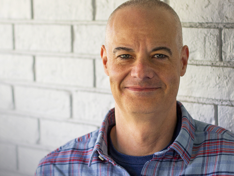 Craig Lindeman standing in front of white brick wall.