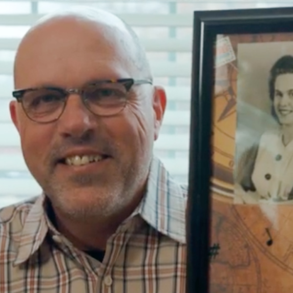 Photo of smiling man holding photo of mother