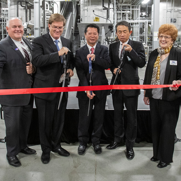 Group of individuals cutting red ribbon