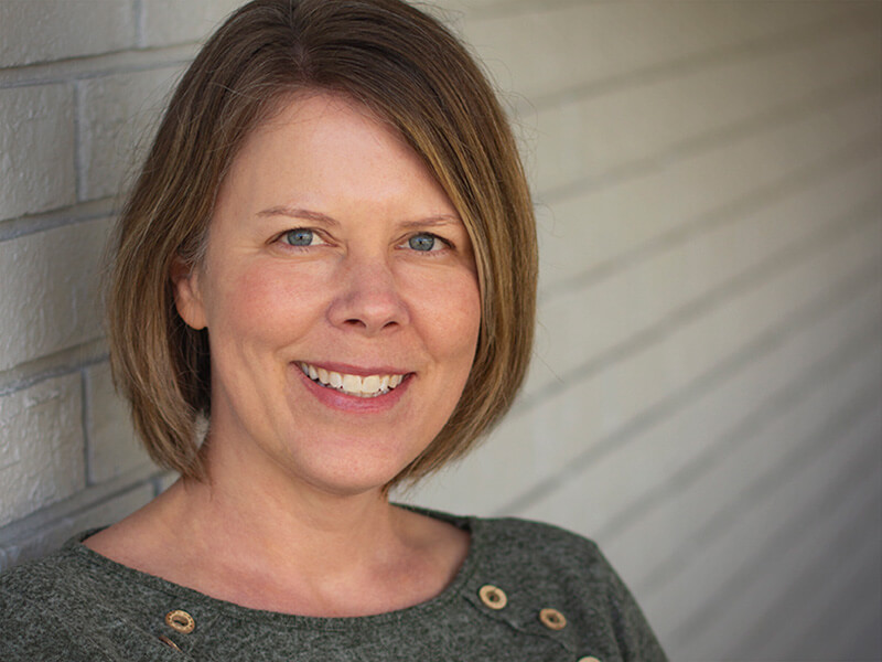 Carrie Lindeman standing in front of white brick wall.